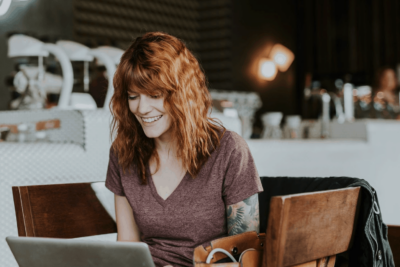 Happy woman smiling at laptop in a coffe shop